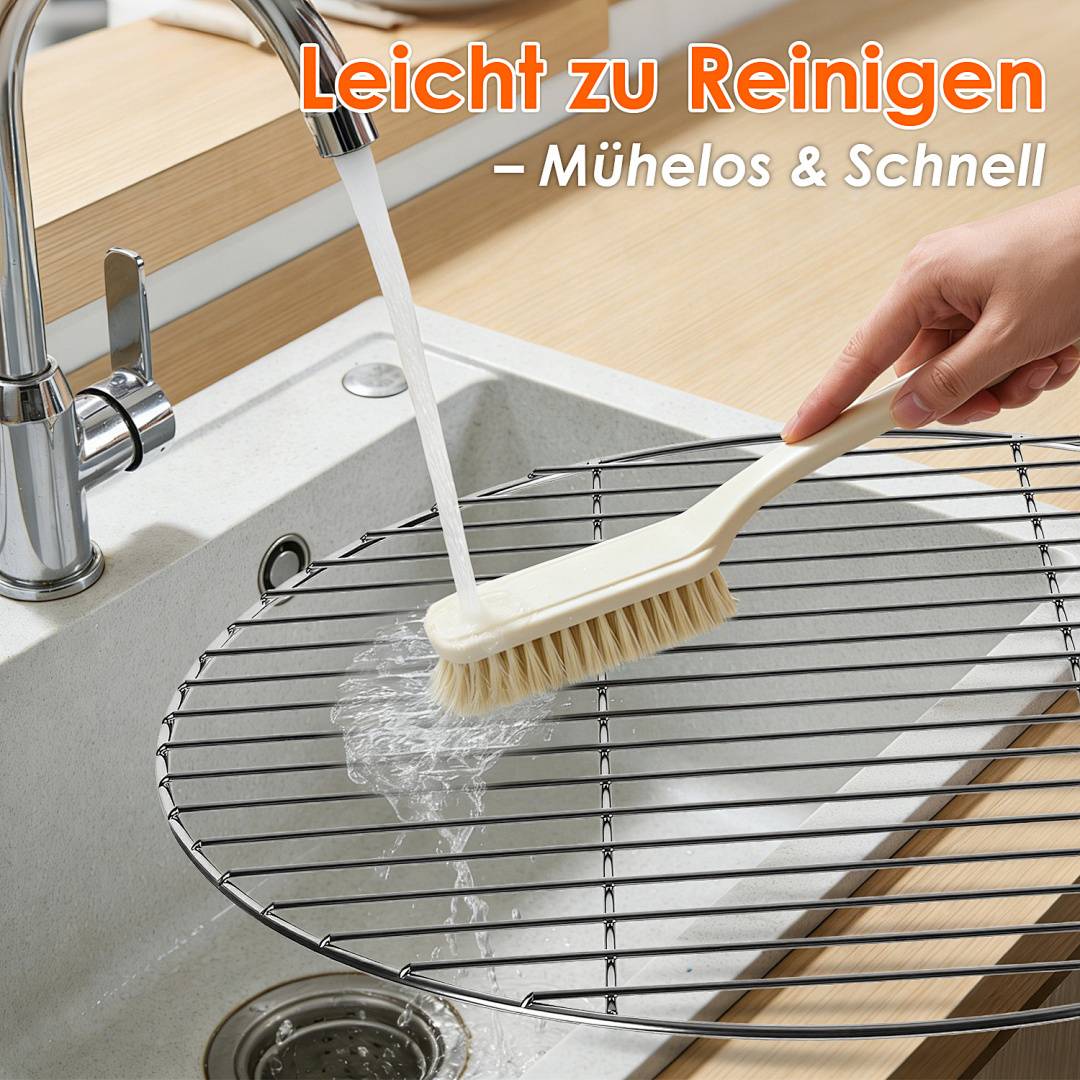 Eine Hand reinigt ein rundes Drahtgitter mit einer Bürste unter fließendem Wasser in einer Küchenspüle. Der deutsche Text lautet „Leicht zu Reinigen - Mühelos & Schnell.