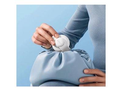 Eine Person, die ein weißes kompaktes Gerät in eine hellblaue Handtasche legt und dabei ein blaues Langarmshirt trägt.