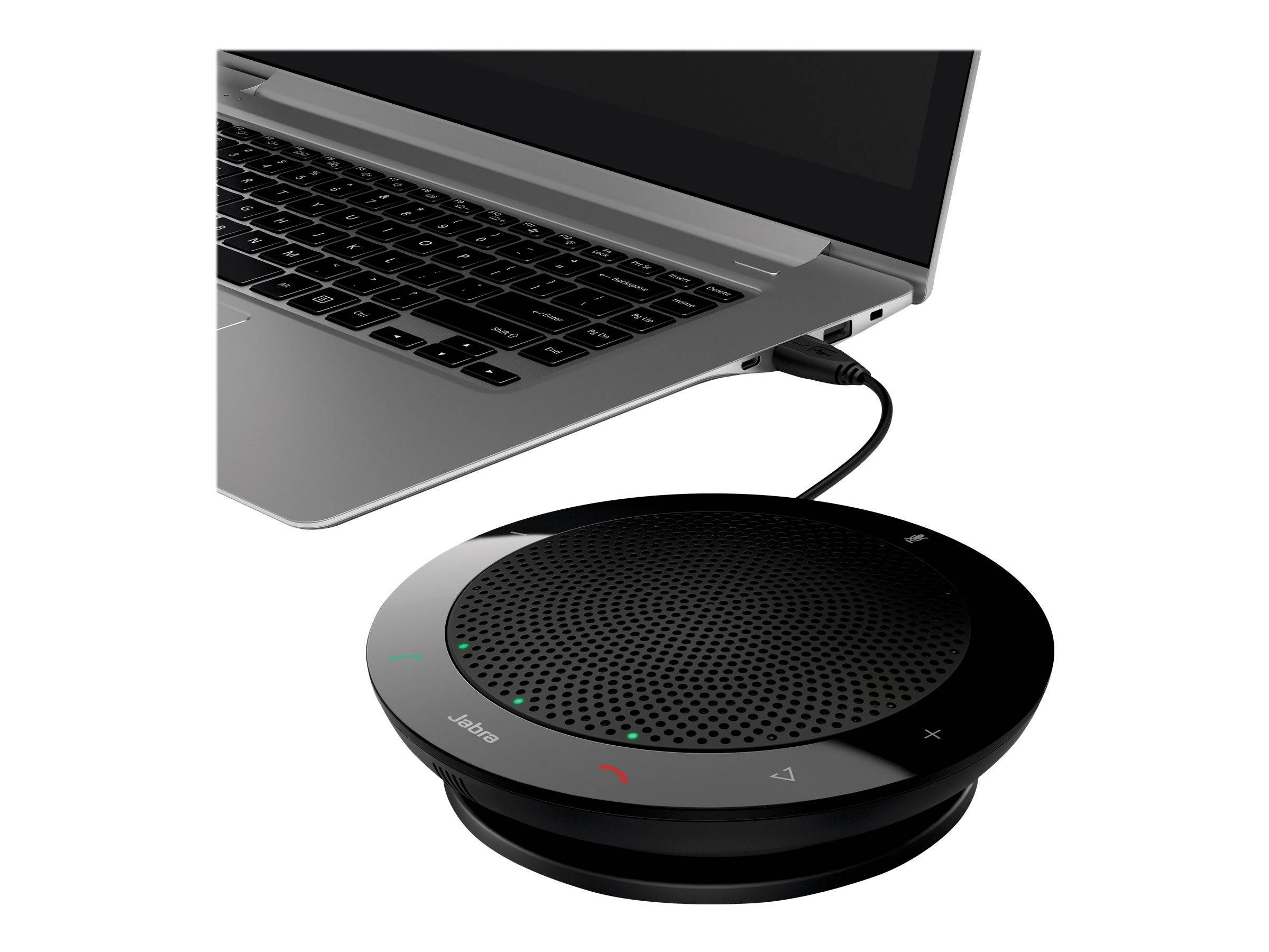 Ein Laptop ist über ein USB-Kabel mit einem runden schwarzen Freisprechgerät verbunden, was auf die Verwendung für Audiokonferenzen hindeutet.