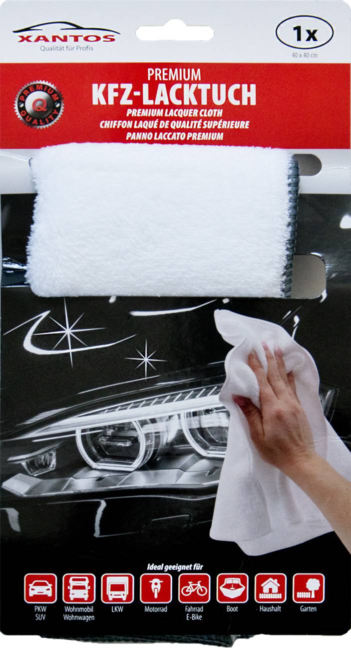 Eine Person, die ein weißes Tuch verwendet, um das glänzende Scheinwerferlicht eines schwarzen Autos zu wischen, wobei die Reinigung und Wartung von Fahrzeugen hervorgehoben wird.