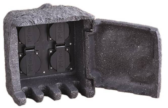 Eine schwarze Box mit abgerundeten Kanten, vier kreisförmige Fächer mit Symbolen und Zahlen, umgeben von Schaumstoffpolsterung zum Schutz.