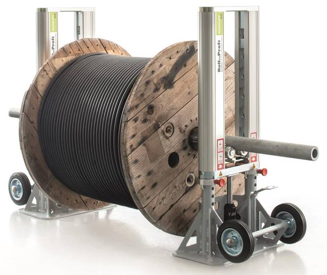 Eine große Holzspule mit schwarzem Kabel ist auf einem Metallspulenständer montiert. Der Ständer ist industriell ausgeführt und verfügt über verstellbare Arme und Räder.