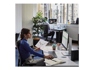 Ein Büro mit einer Person, die an einem Schreibtisch sitzt und einen Computer nutzt, um ein Diagramm zu analysieren. Eine andere Person ist sichtbar, die an einem separaten Schreibtisch arbeitet.