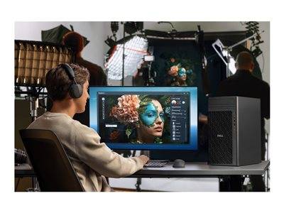 Eine Person mit Kopfhörern sitzt an einem Schreibtisch und verwendet Software auf einem Computer, um ein Bild einer Person mit Blumenschminke zu bearbeiten. Fotografische Beleuchtung und ein Studio-Setup sind im Hintergrund sichtbar.