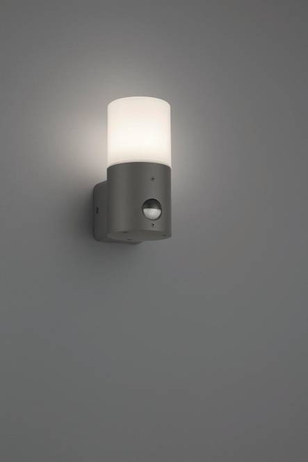 Eine moderne, an der Wand montierte Leuchte mit einem zylindrischen Lampenschirm aus mattiertem Glas und einem Bewegungsmelder vor einem grauen Hintergrund.