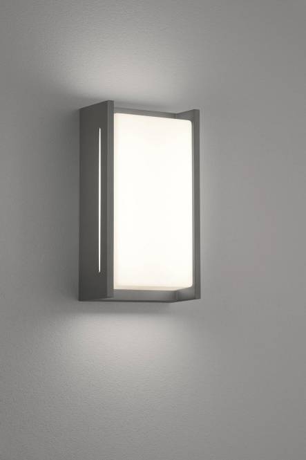 Eine moderne, rechteckige Wandleuchte mit warmem weißem Licht, an einer schlichten Wand montiert, die Umgebungslicht spendet.