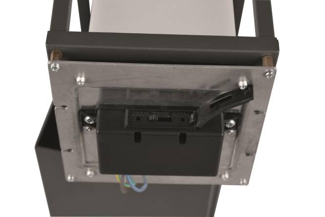 Ein schwarzes Metallbauteil mit Schrauben und Drähten, wahrscheinlich Teil eines größeren mechanischen oder elektronischen Geräts.