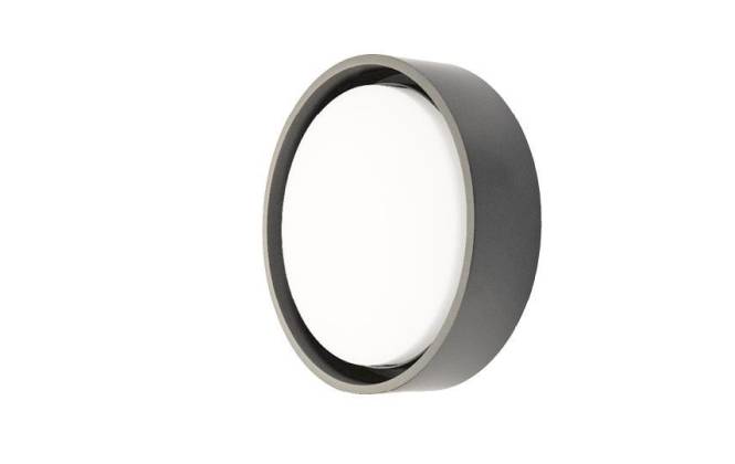 Ein runder, an der Wand montierter Spiegel mit einem dicken, dunklen Rahmen, aus einem leicht schrägen Blickwinkel betrachtet.