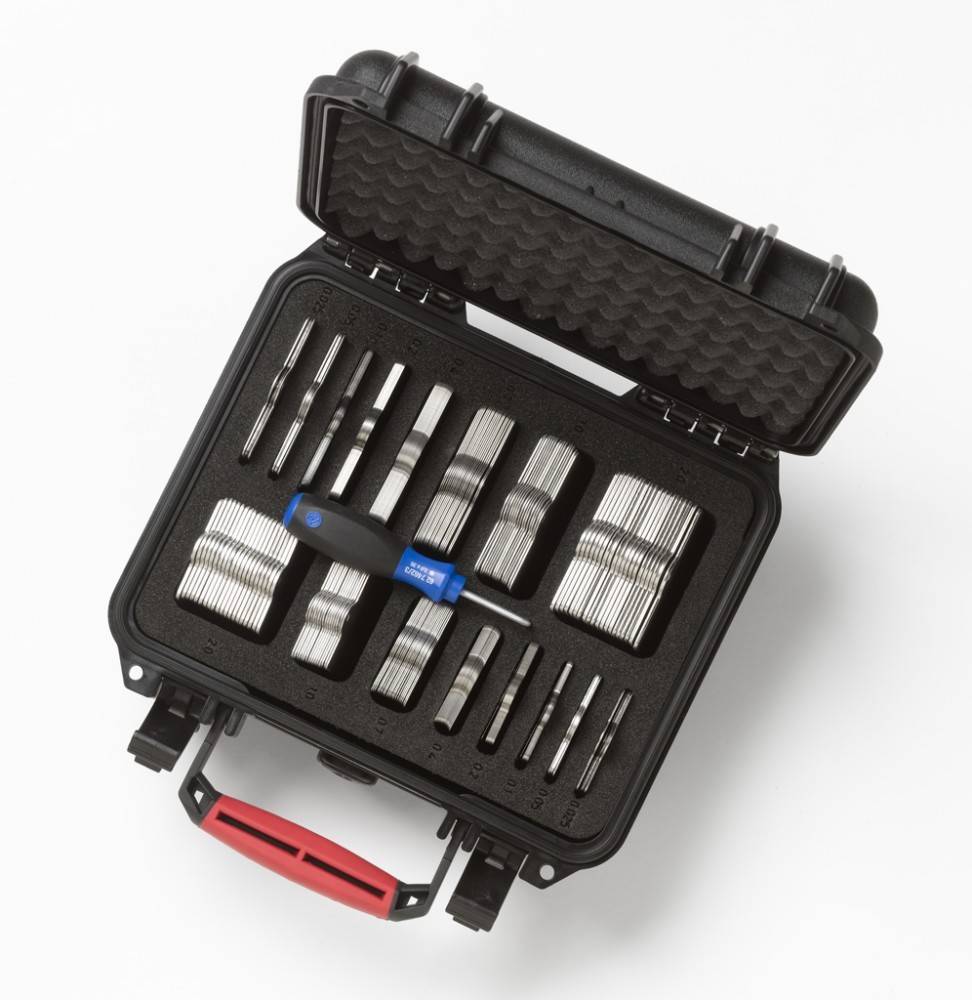 Ein schwarzer Werkzeugkasten mit organisierten Reihen von Bohrern und einem Schraubendreher mit blauem Griff im Inneren. Der Kasten hat einen roten Griff und Schaumstoffpolsterung.