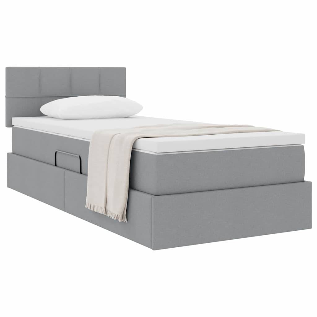 Ein graues gepolstertes Einzelbett mit Kopfteil, weißem Kissen und beigem Wolldecke, mit einer Schublade an der Seite zur Aufbewahrung.