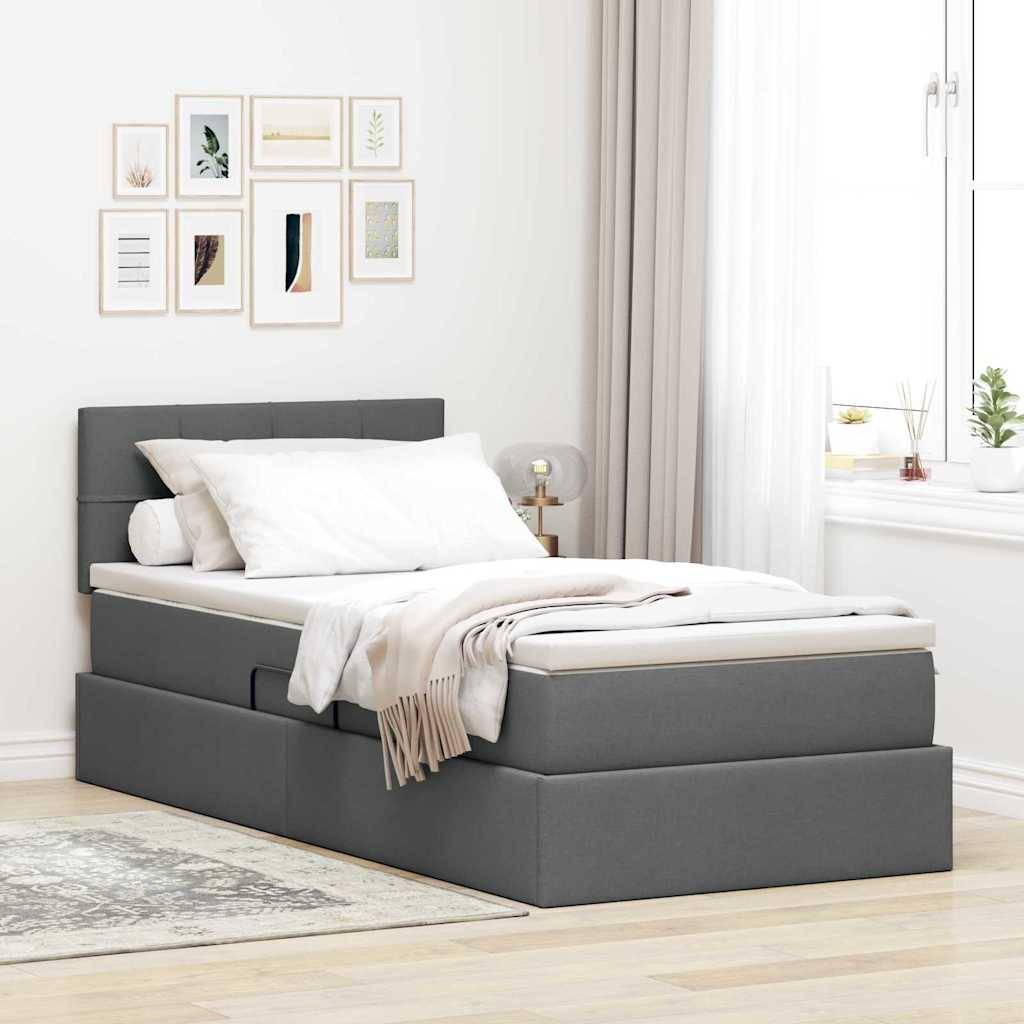 Ein modernes Schlafzimmer mit einem grau gepolsterten Bett, weißer Bettwäsche und einer beigen Wurfdecke. Kunstwerke hängen an der Wand darüber. Natürliches Licht fällt durch ein Fenster herein.