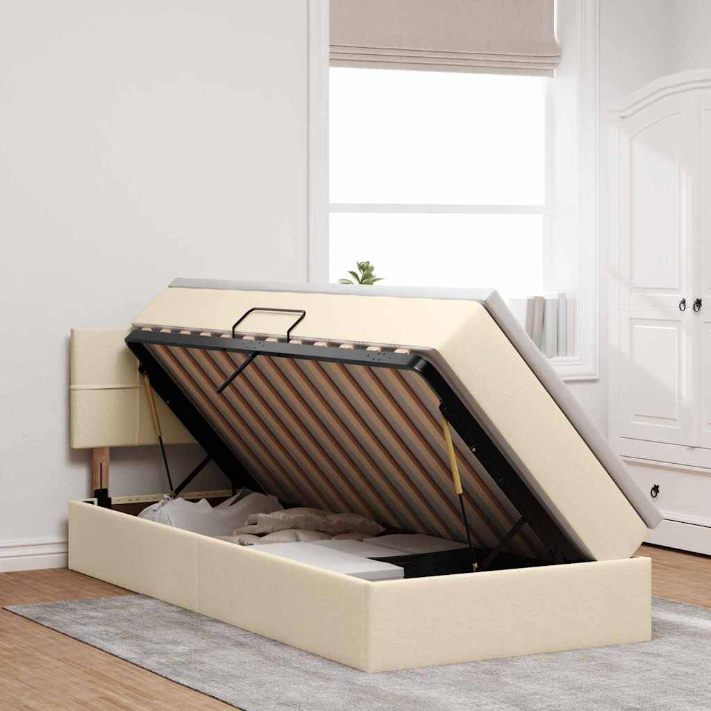 Ein beiges Ottomanbett mit teilweise angehobener Matratze, die den Stauraum darunter offenbart. Positioniert in einem hellen Zimmer mit Holzboden.