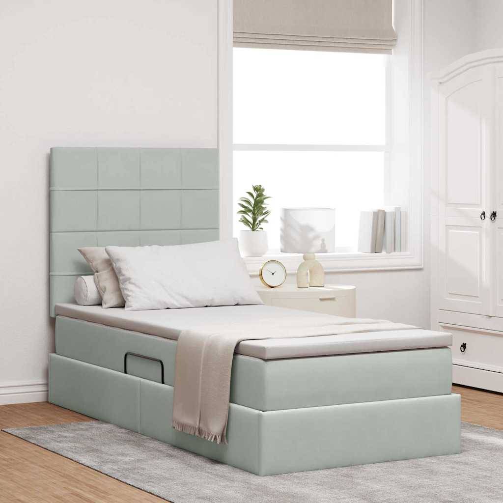 Ein modernes Schlafzimmer mit einem Einzelbett, das ein gepolstertes Kopfende, Kissen und eine Decke hat. Ein Fenster und ein kleiner Nachttisch mit Dekoration sind sichtbar.
