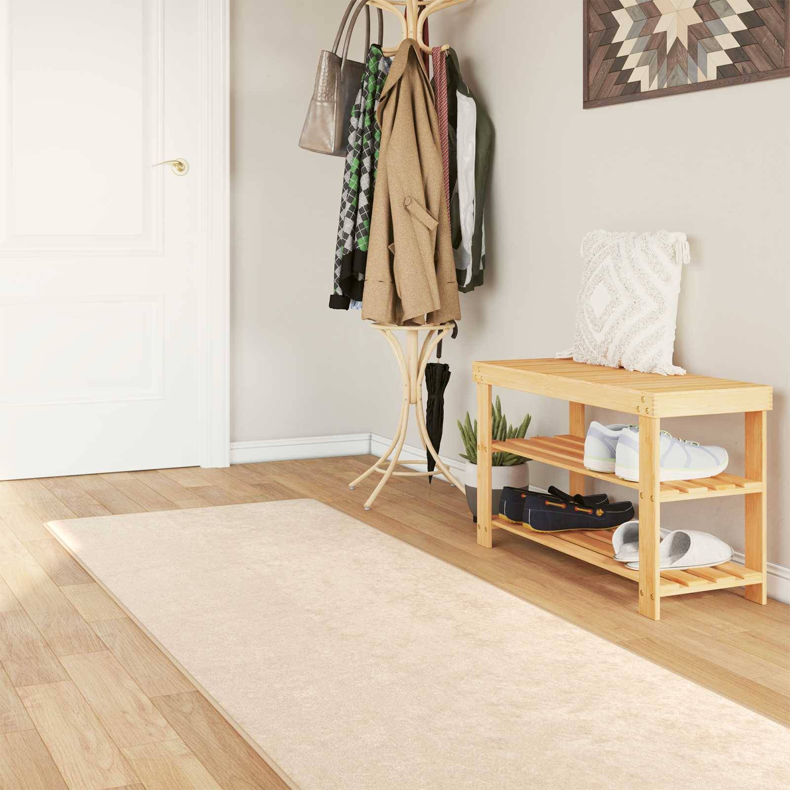 Gemütlicher Flur mit einer Garderobe, die Kleidung hält, einem kleinen Holzschuhregal mit weißen Sneakern und einem gemusterten Teppich auf einem Holzboden.
