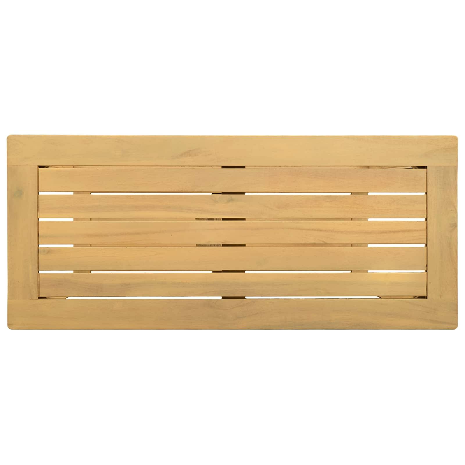 Eine graue Lagerbank mit einer schwarzen Tasche oben darauf steht an einer Wand. Eine dekorative Pflanze befindet sich auf der rechten Seite, und weiße Hausschuhe liegen auf dem Boden davor.