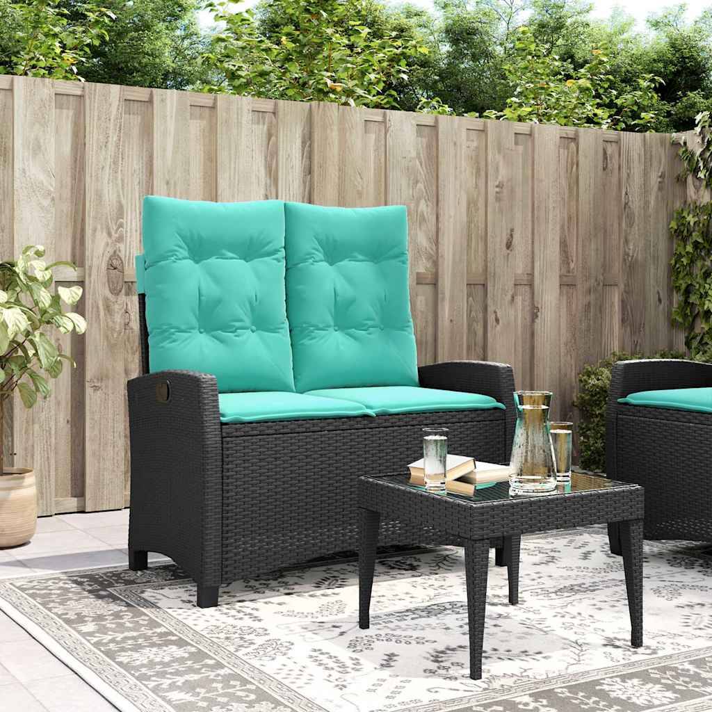 Außenbereich-Terrassenszenerie mit Korbmöbeln: türkisfarbiges Sofa und Stühle mit Kissen, kleiner Tisch mit Glastischplatte und Gläsern, Holzzaun im Hintergrund.