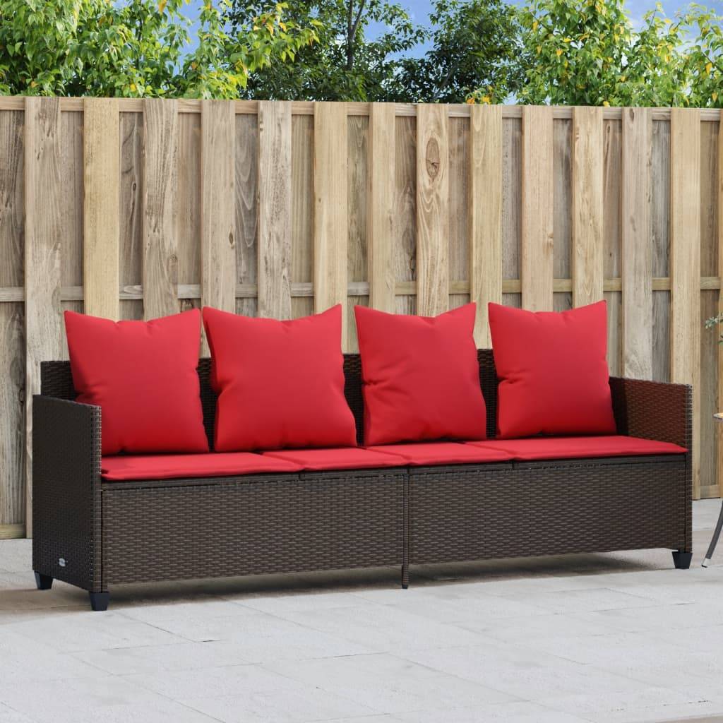 Outdoor-Terrasse mit Holzzaun und braunem Rattan-Sofa. Das Sofa verfügt über rote Kissen und Polster und steht auf einem Steinfliesenboden.