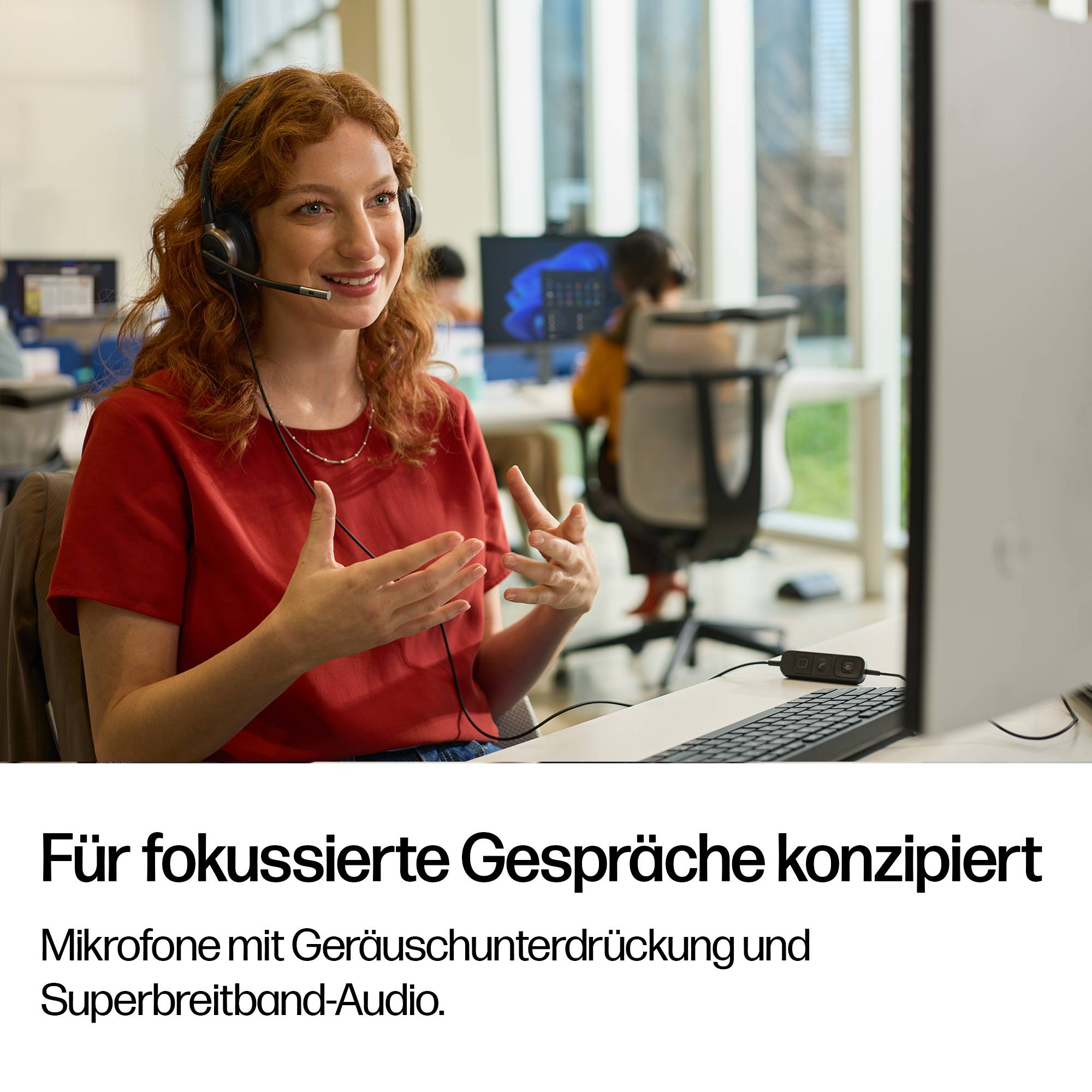 Frau mit Kopfhörer spricht an einem Schreibtisch in einem hellen Büro; Deutscher Text unten lautet „Für fokussierte Gespräche konzipiert