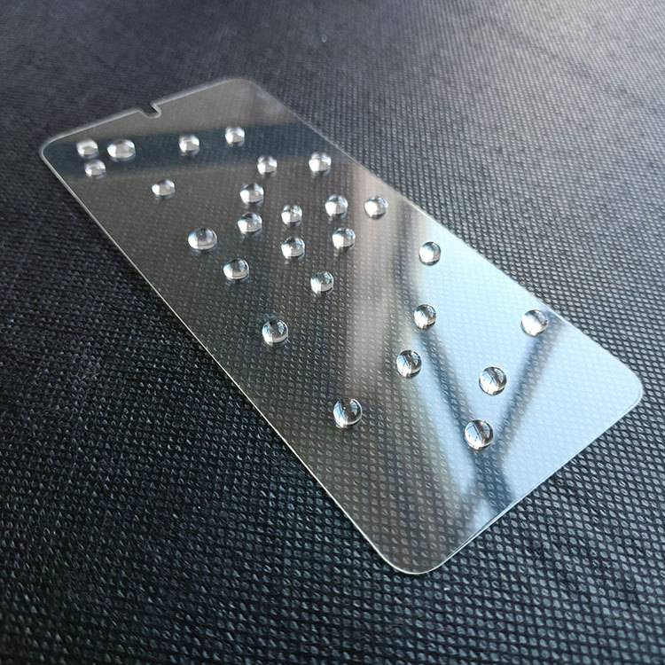 Ein Displayschutz für Telefone mit Wassertropfen darauf, die seine wasserabweisenden Eigenschaften hervorheben, platziert auf einer dunklen strukturierten Oberfläche.