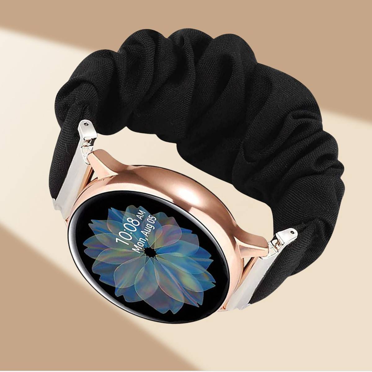 Eine rosegoldfarbene Smartwatch mit einem schwarzen Scrunchie-ähnlichen Armband zeigt die Uhrzeit „10:08 AM