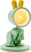 Eine grüne, modern aussehende Kunststofflampe mit zylindrischem Schirm, eingeschaltet mit warmem Licht, das eine gemütliche Atmosphäre schafft.