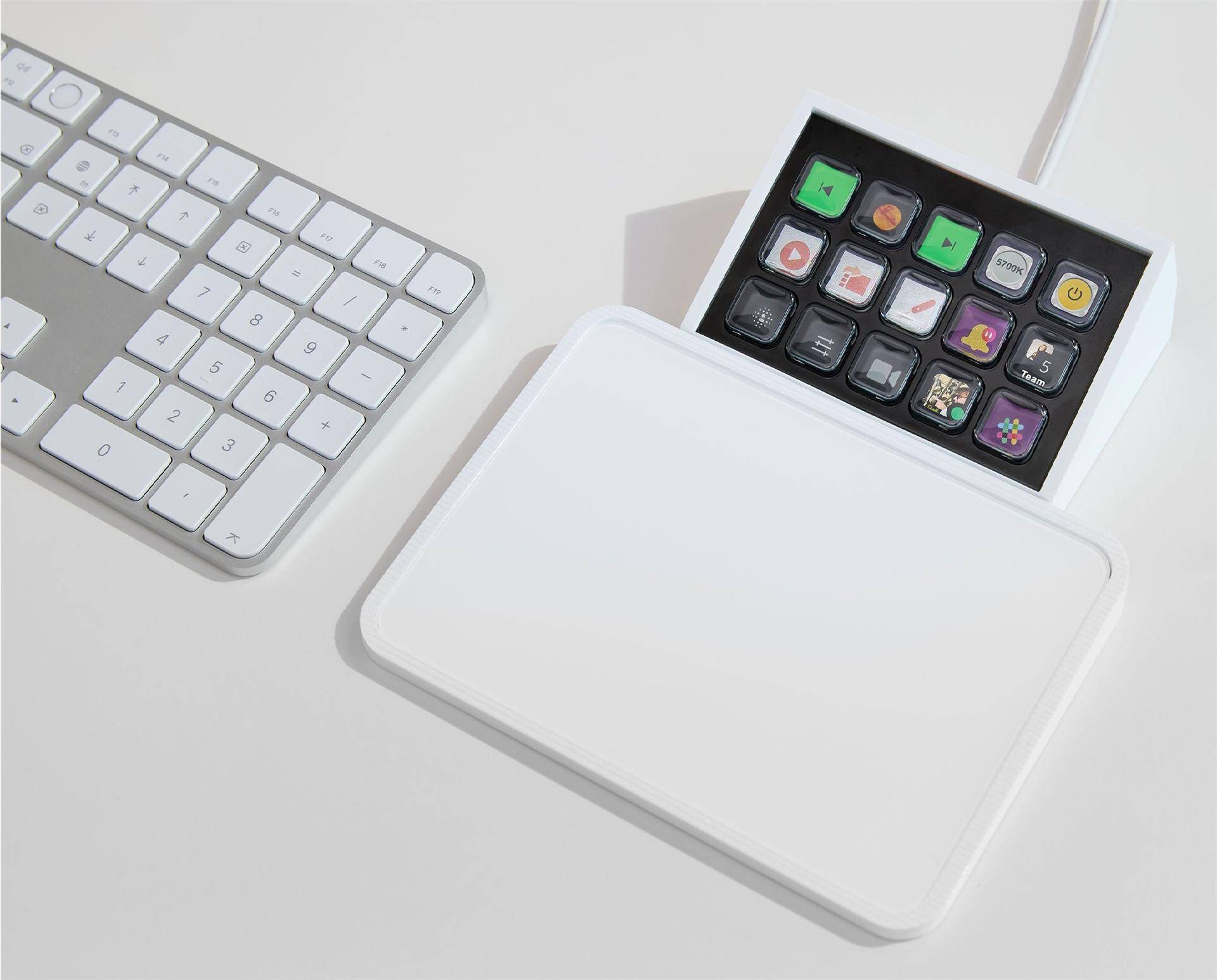 Eine Tastatur und ein anpassbares Tastenfeld mit farbig beschrifteten Tasten sind auf einer weißen Oberfläche platziert und unterstreichen Technologie und Personalisierung.