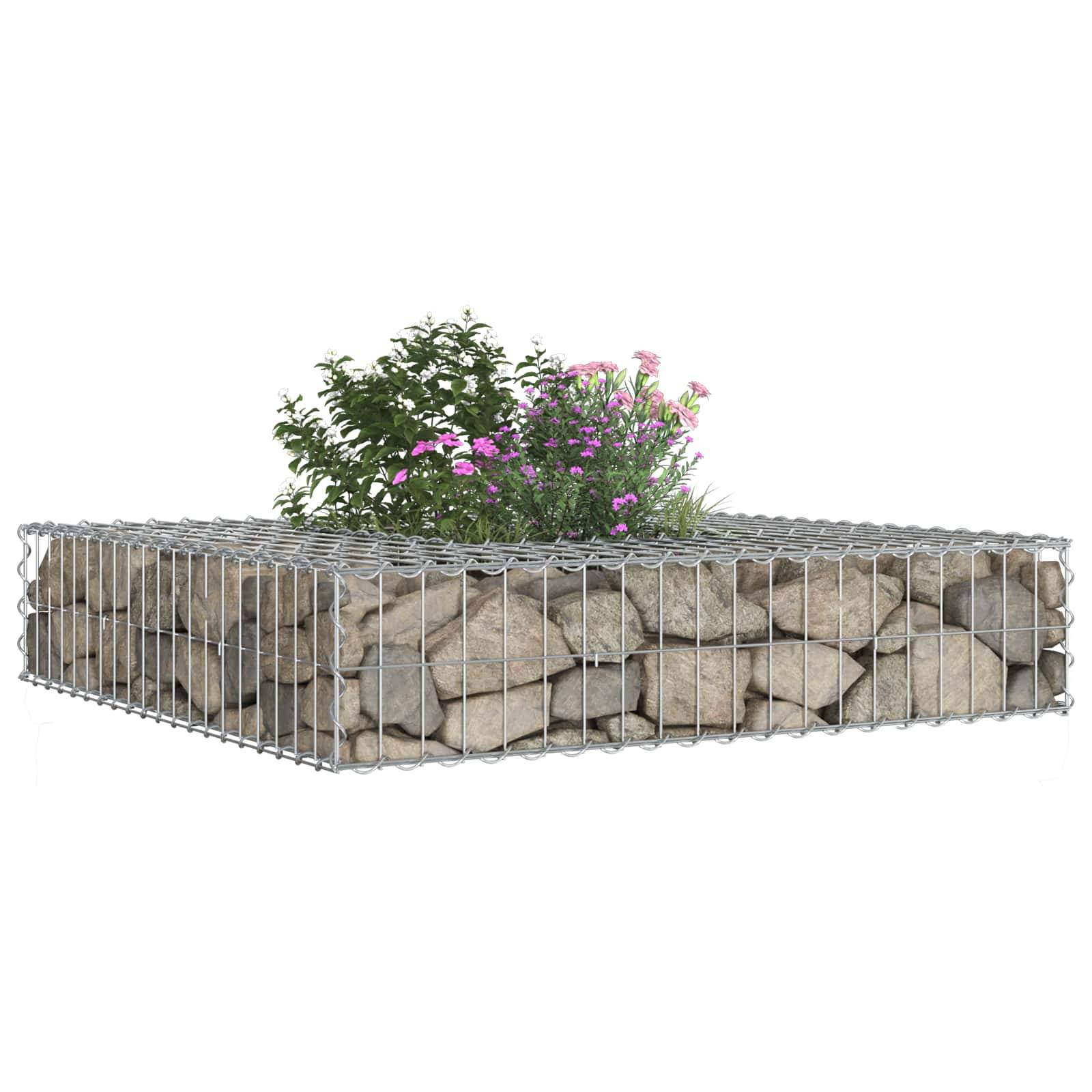 Ein Maschendrahtkäfig gefüllt mit Steinen bildet ein erhöhtes Gartenbeet, mit grünen Pflanzen und rosa Blüten, die oben wachsen, isoliert auf weißem Hintergrund.