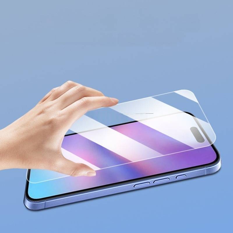 Eine Hand bringt einen durchsichtigen Displayschutz auf einem Smartphone mit violettem Display gegen einen blauen Hintergrund an.