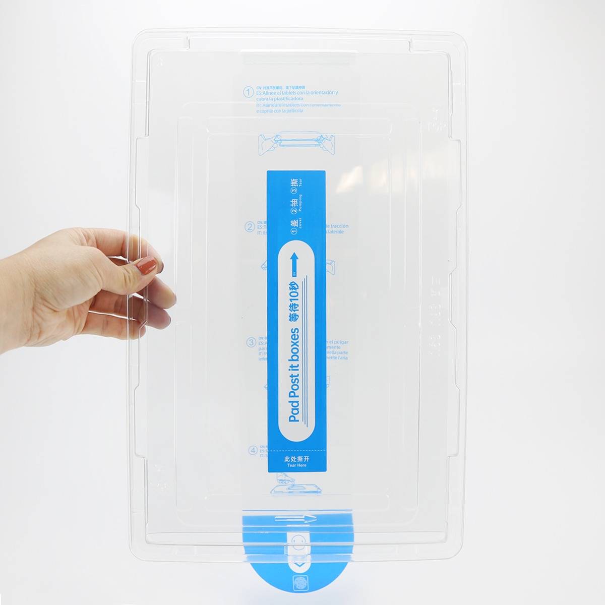 Hand hält eine transparente Kunststoff-Aufbewahrungsbox mit blauem Mitteletikett, gezeigt auf weißem Hintergrund.