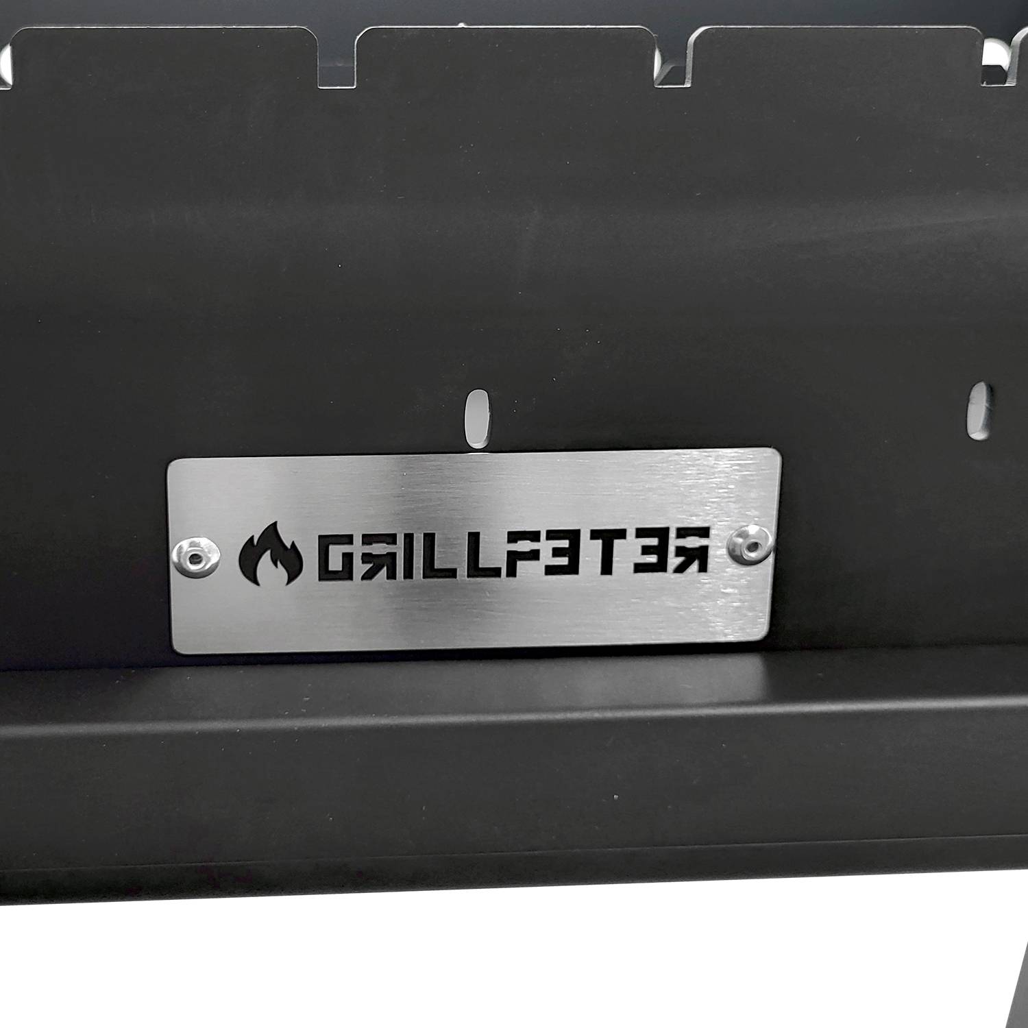Eine Metallplatte auf einem Grill zeigt ein Logo mit einer Flamme und dem Text „GRILLPETER".