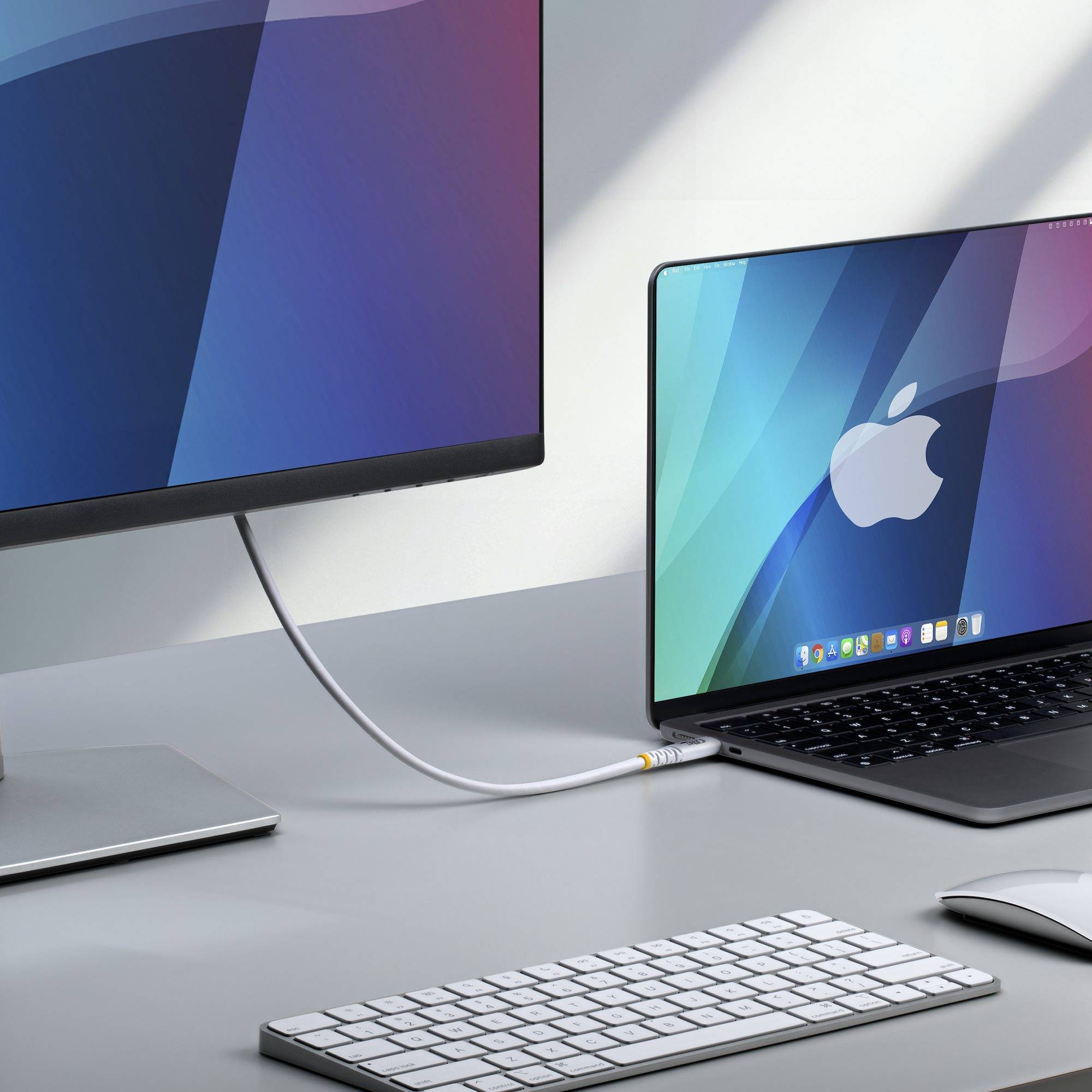 Ein Apple-Laptop, der an einem Schreibtisch mit einem externen Monitor verbunden ist, mit einer Tastatur und einer Maus, die ein Desktop-Setup zeigen.