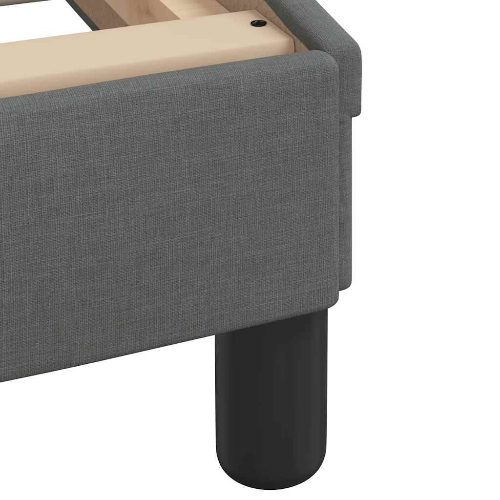 Nahaufnahme einer Ecke eines grau gepolsterten Sofas mit einem schwarzen zylindrischen Bein und hellholzerner Oberkante.