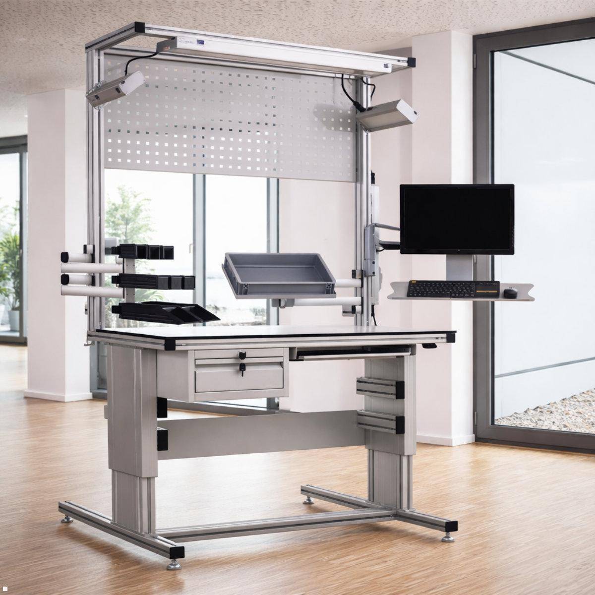 Verstellbare Industriearbeitsstation mit Monitor, Tastaturablage, Dokumentenablage und Werkzeughaltern in einer hellen Büroumgebung.