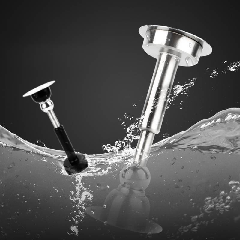 Zwei aus Edelstahl gefertigte Duschabfluss-Stöpsel oder Verschlüsse, die teilweise in spritzendem Wasser gegen einen dunklen Hintergrund eingetaucht sind.