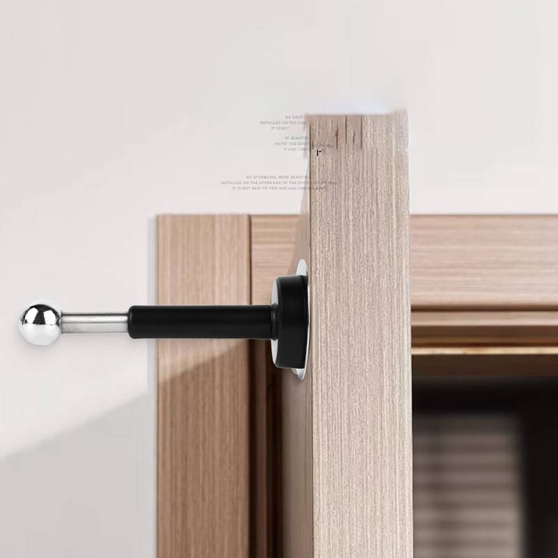 Nahaufnahme eines schwarzen und verchromten verstellbaren Türstopper, der an einem Holz-Türrahmen montiert ist und verhindert, dass die Tür gegen die Wand schlägt.
