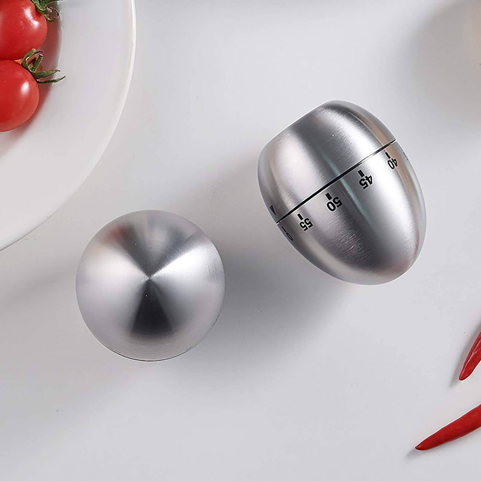 Zwei Edelstahl-Eierförmige Küchentimer auf einer weißen Oberfläche, einer mit Minutenmarkierungen, mit Tomaten und roten Chilis an den Rändern.