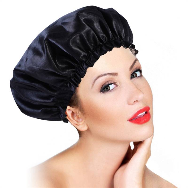 Porträt einer Frau, die eine schwarze Satin-Duschhaube trägt, mit rotem Lippenstift und ihrer Hand unter dem Kinn auf weißem Hintergrund.