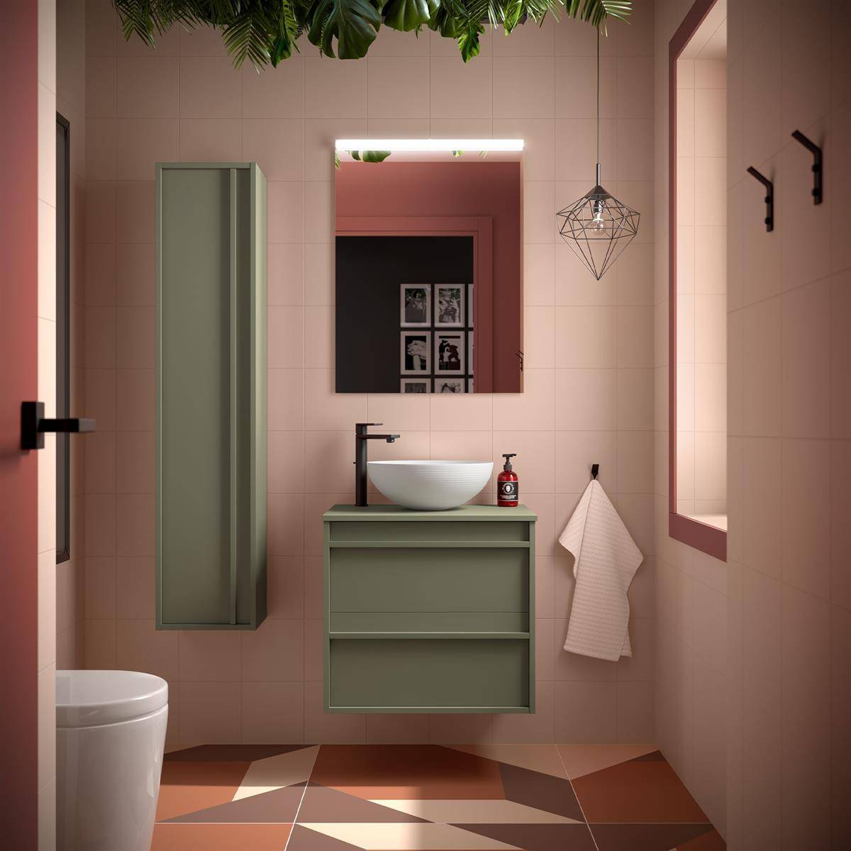 Modernes rosa Badezimmer mit Toilette, grüner Waschtisch und Spiegel, Wandschrank, Pendelleuchte, Handtuch und geometrischen Bodenfliesen.