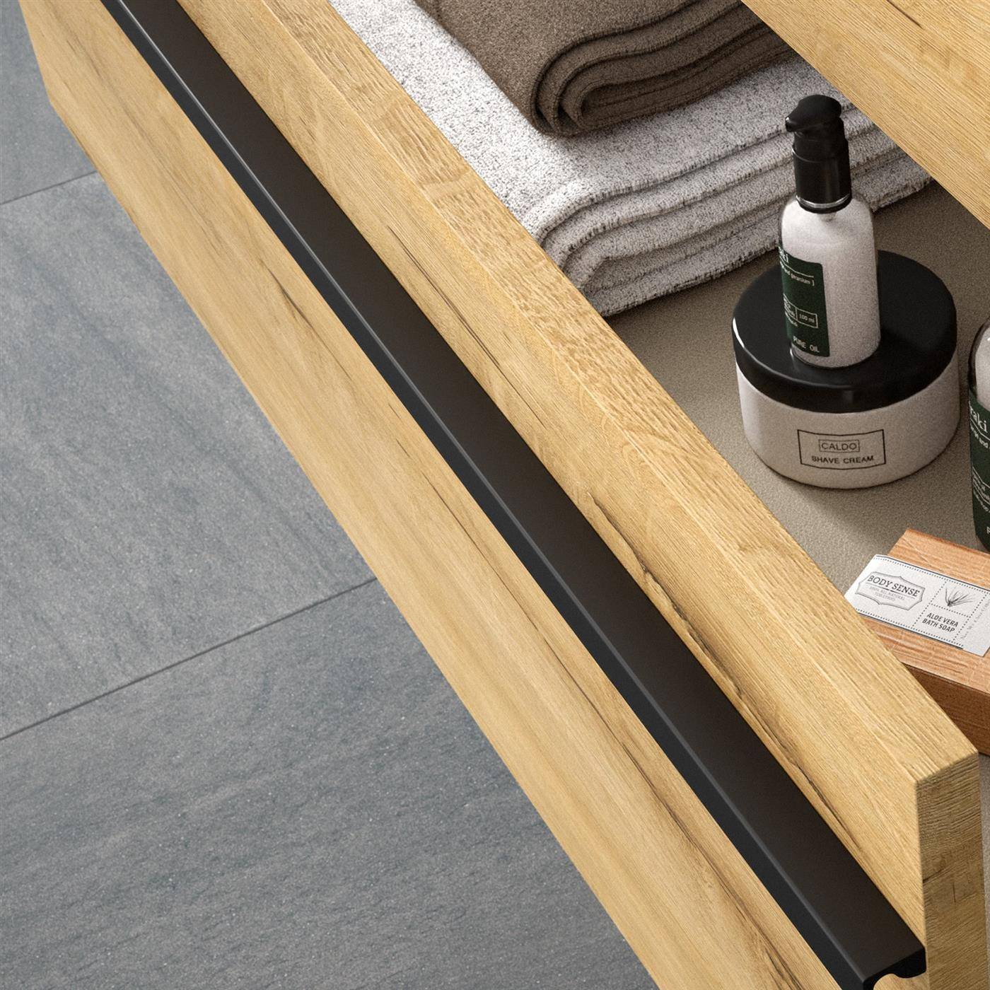 Offene Holzschublade in einem Badezimmerschrank mit gefalteten Handtüchern und Toilettenartikelfläschchen, mit einem schwarzen Aufbewahrungstablett an der vorderen Kante.