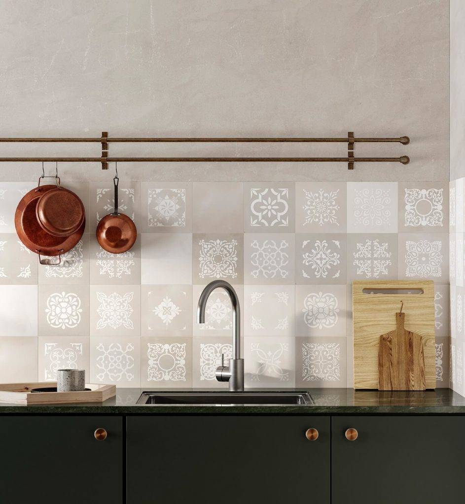 Moderne Küchenküchenrückwand mit gemusterten beigefarbenen Fliesen, hängenden Kupfertöpfen, einem Waschbecken und Wasserhahn sowie dunkelgrünen Schränken mit Kupferknöpfen.