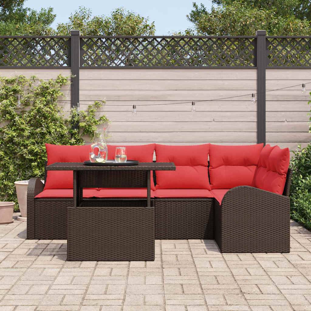 Outdoor-Sitzgarnitur auf einer gepflasterten Terrasse mit roten Kissen und dunkelm Polyrattan-Sofa, Sessel und Tisch.