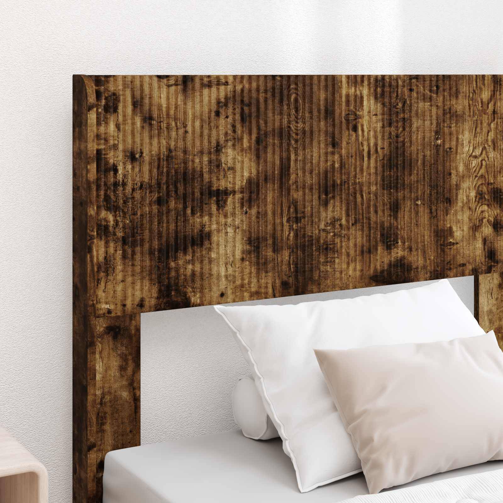 Rustikales Holzkopfbrett mit weißen Bettkissen und Bettwäsche vor einer hellen Wand, das ein einfaches modernes Schlafzimmer-Setup zeigt.