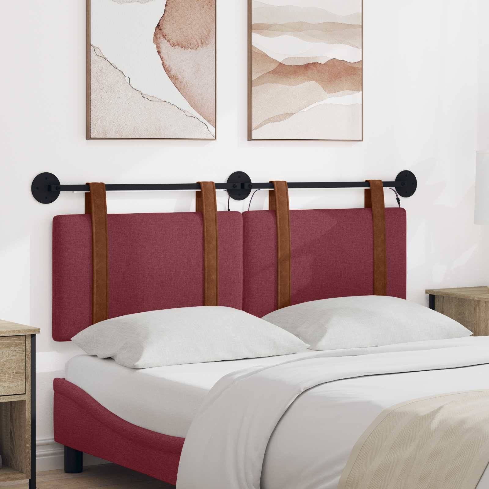 Modernes Bett mit bordeauxfarbenem gepolstertem Kopfteil und Ledergurten, weißer Bettwäsche und zwei abstrakten Wandkunstdrucken darüber.