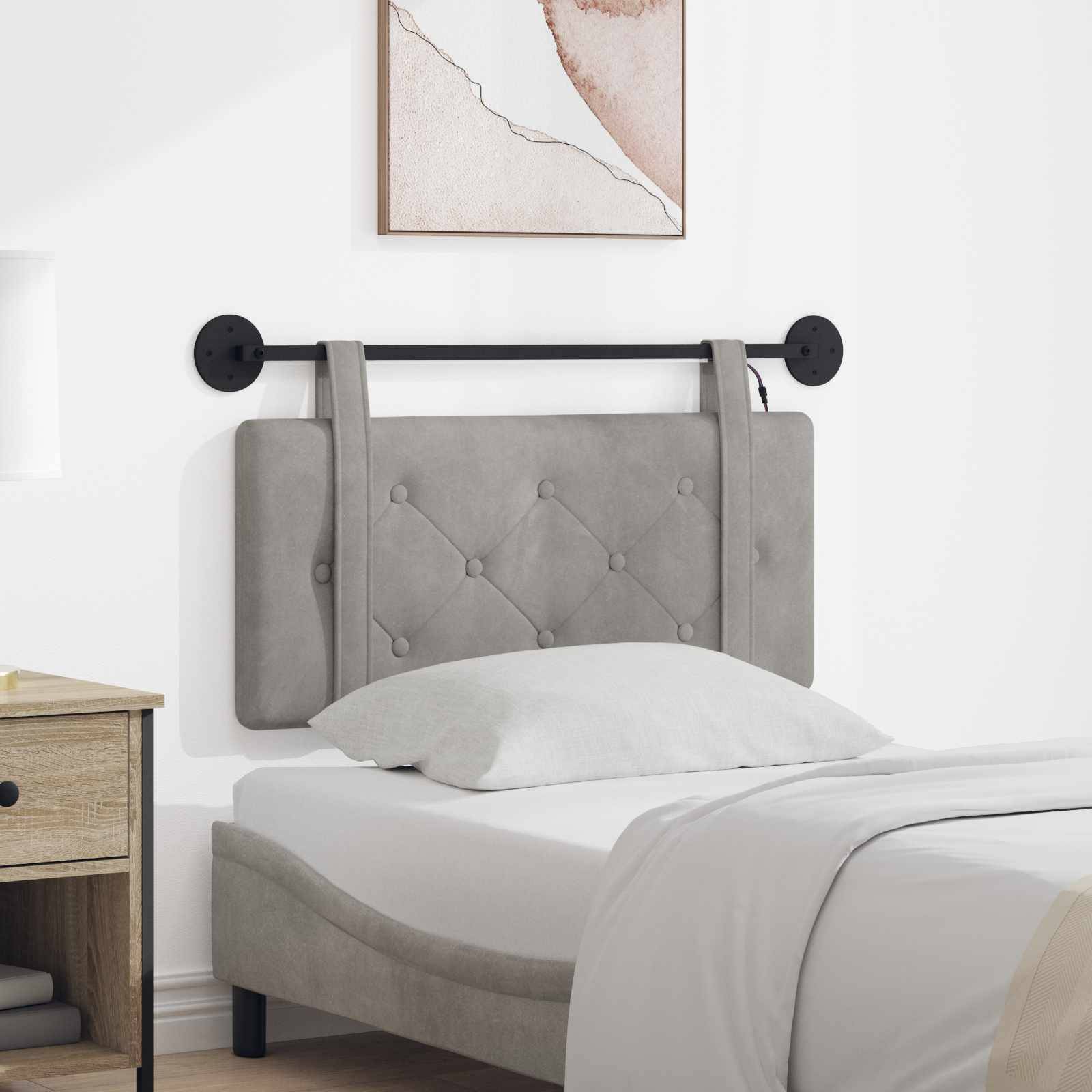Ein grau gepolstertes Bett mit gepolstertem Kopfteil und schwarz wandmontierten Rahmen, ausgestattet mit weißer Bettwäsche in einem minimalistischen Schlafzimmer.