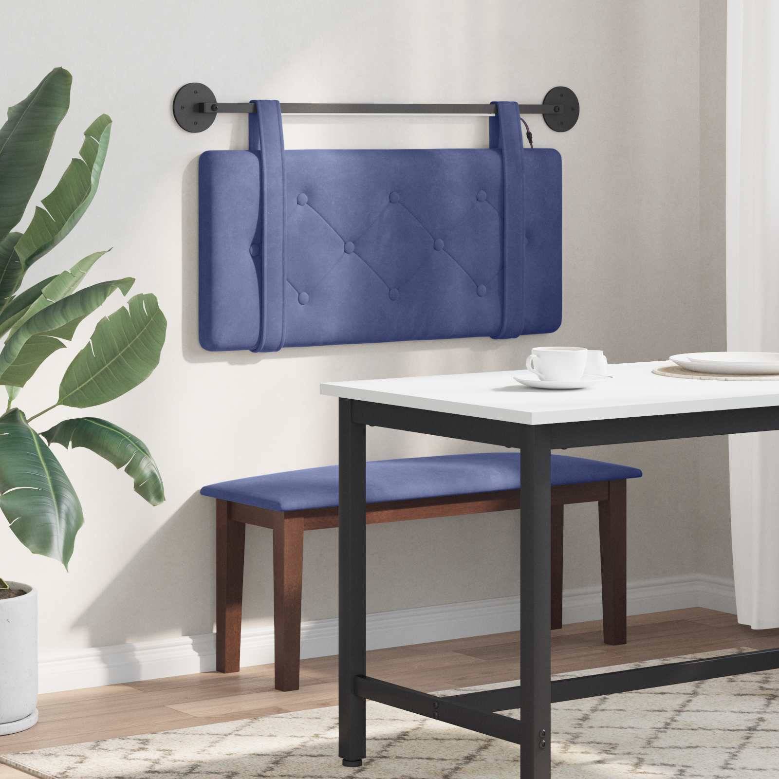 Blaugepolsterte an der Wand montierte Bank mit einer schwarzen Metallstange, neben einem Esstisch und einer Zimmerpflanze in einem modernen Raum.