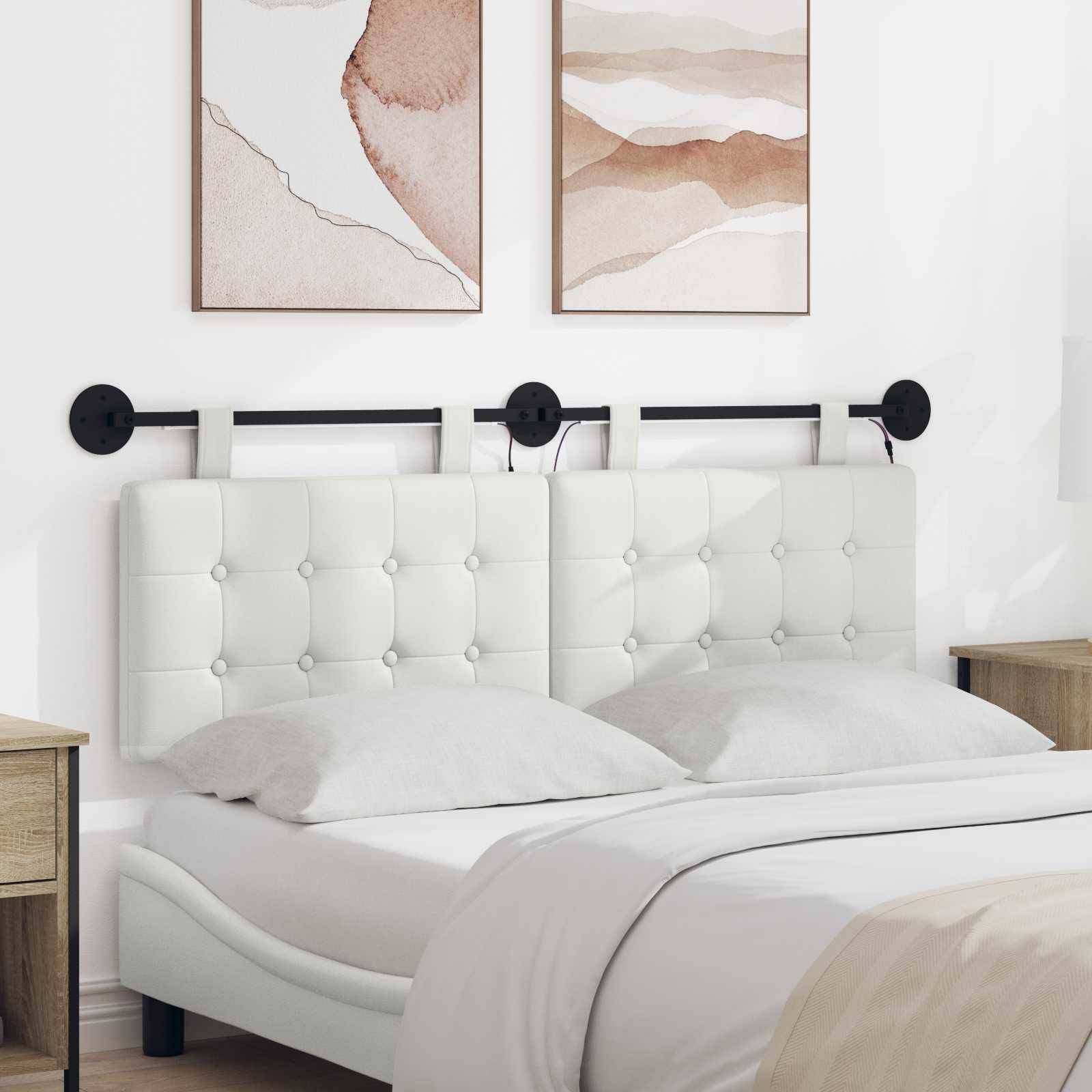 Minimales weißes Schlafzimmer mit einem gesteppten gepolsterten Bett, weißer Bettwäsche, Holz-Nachttischen und zwei abstrakten Wanddrucken über dem Kopfende des Bettes.