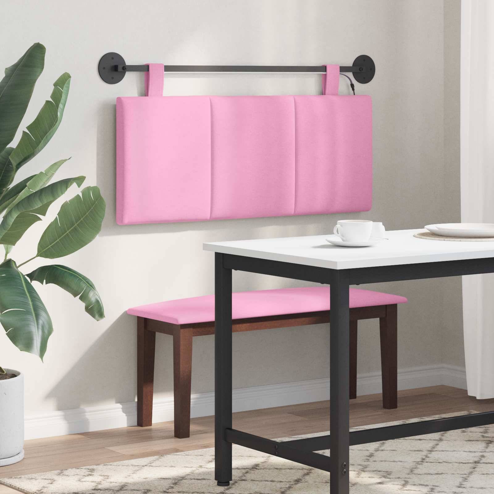 Rosa gepolsterte, wandmontierte Bankenlehne über einer Speisebankablage neben einem weißen Tisch in einem hellen, modernen Raum mit einer Topfpflanze.