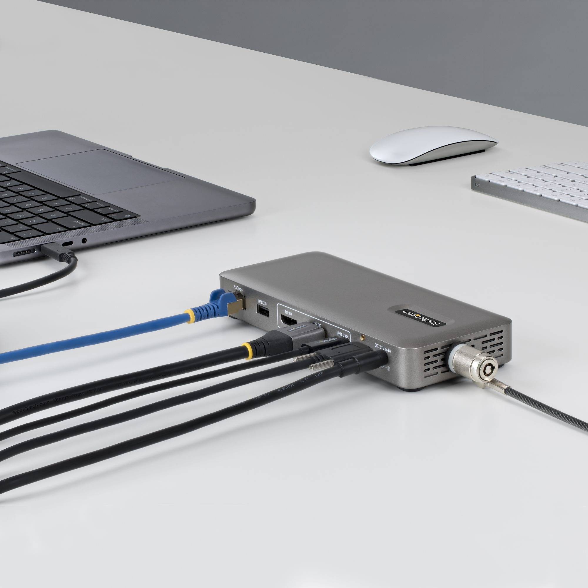 Laptop, die über Ethernet und andere Kabel mit einem kleinen Netzwerkgerät auf einem Schreibtisch verbunden ist, mit Maus und Tastatur in der Nähe.