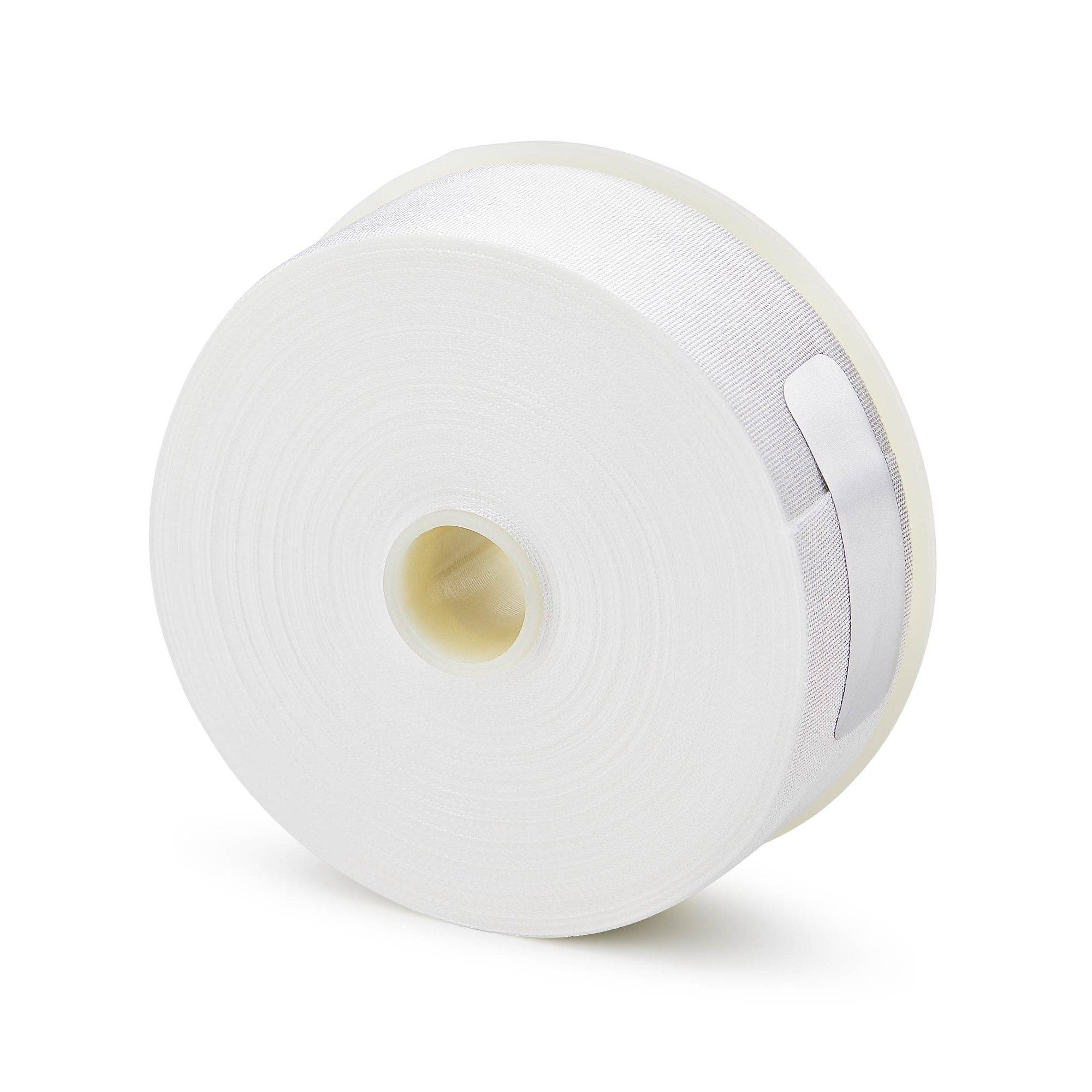 Eine große weiße Rolle Klebeband oder Verbandsmaterial mit einem hohlen Papierwickel im Innern, dargestellt vor einem einfachen Hintergrund.