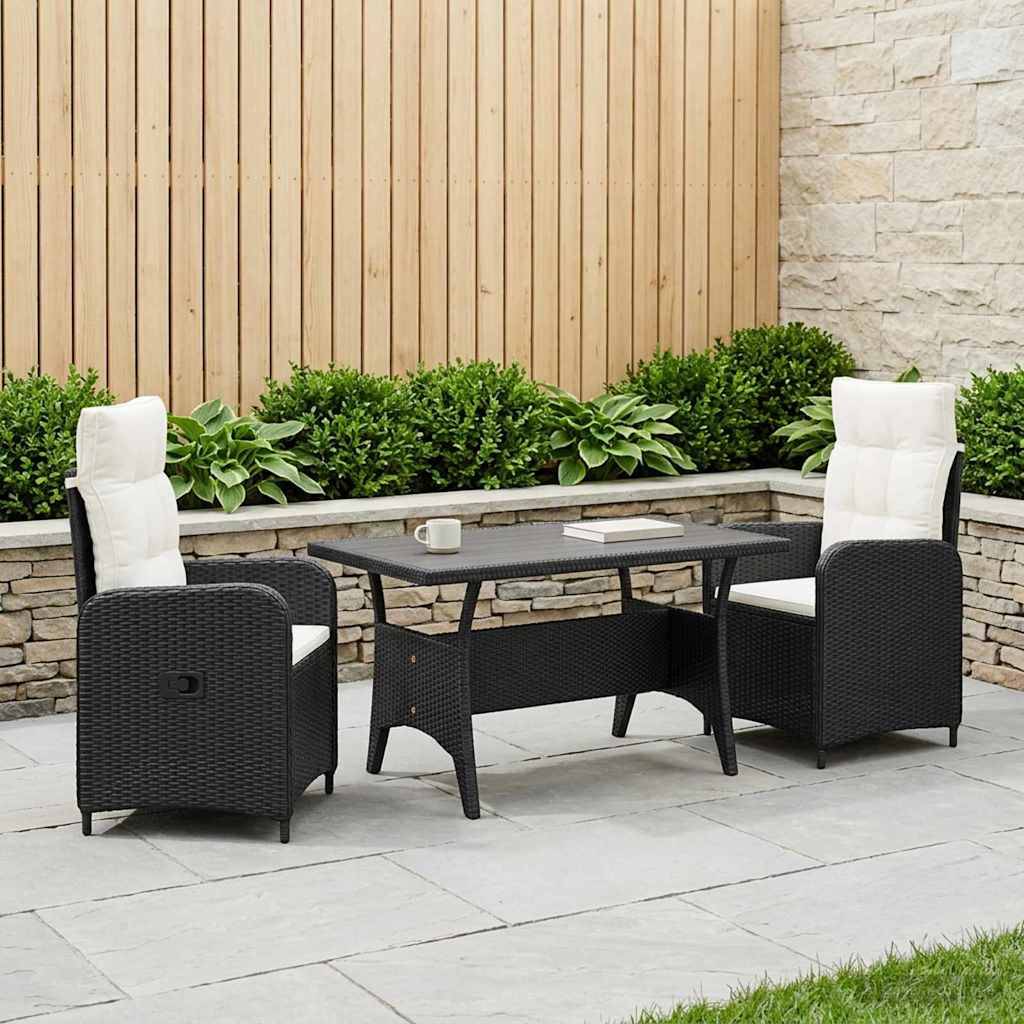 Gartenbereich zum Essen mit zwei gepolsterten schwarzen Rattanstühlen und einem passenden Tisch auf einer Steinterrasse, neben einem bepflanzten Beet und einem Holzzaun.